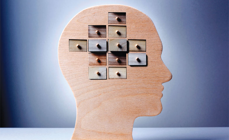 Wooden head silhouette with tiny drawers in the brain area against a blue gradient background, suggesting memory or organization.